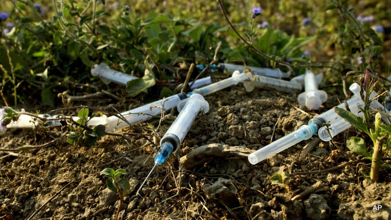 Freshly dumped Hypodermic syringes and a needle litter an abandoned cemetery. (AP)
