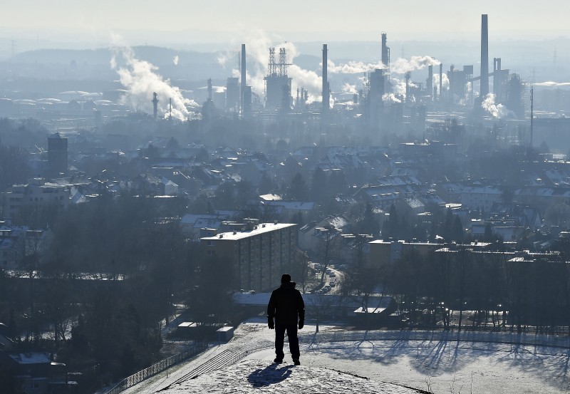 A man watches a steaming BP refinery in the city of Gelsenkirchen, on a frosty but sunny winter Tuesday, Jan. 19, 2016. Millions of customers benefit from the low heating oil prizes this winter. (AP Photo/Martin Meissner)