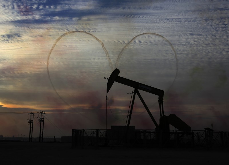 An oil pump works as Al Fursan, the aerobatics demonstration team of the United Arab Emirates Air Force performs during the Bahrain International Airshow in Sakhir, Bahrain, Saturday, Jan. 23, 2016. (AP Photo/Hasan Jamali)