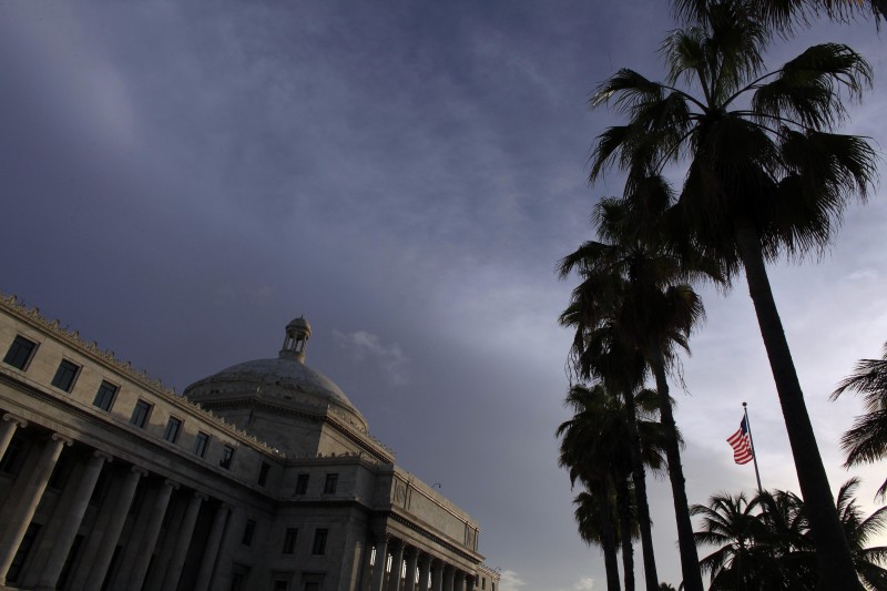 In this July 29, 2015 file photo, the U.S. flag flies in front of Puerto Ricos Capitol in San Juan, Puerto Rico. The government released on Tuesday, Feb. 17, 2106 a long-awaited draft of its financial report that warns of solvency issues as it pushes to obtain a restructuring mechanism from U.S. Congress to deal with its public debt. (AP Photo/Ricardo Arduengo, File)