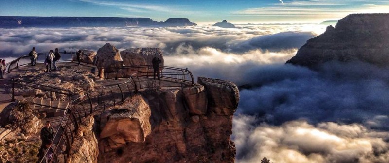 A few tourists stand on a cliff overlooking the Grand Canyon, which is filled with dense fog in this Nov. 29, 2013 photograph. (Wikimedia Commons / U.S. National Park Service / Erin Whittaker)