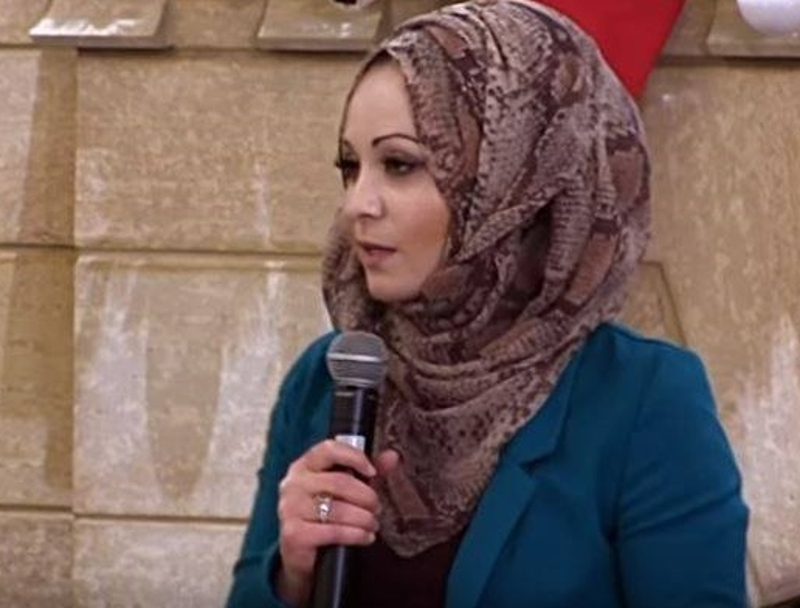 Mnar Muhawesh speaks on a microphone.