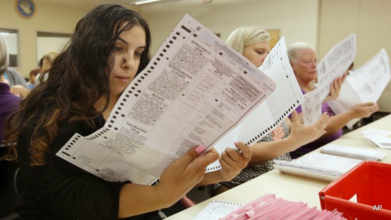 Sabrina Riddle, left, a temporary worker at the Sacramento County Registrar of Voters office, inspects a mail-in ballot Monday, June 6, 2016, in Sacramento, Calif. Voter turnout is expected to be higher then normal in the nation's most populous state for Tuesday's presidential primary. (AP Photo/Rich Pedroncelli)