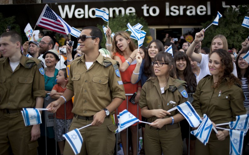 Israeli soldiers and relatives of new Jewish immigrants from the U.S. and Canada, wave Israeli flags to welcome them as they arrive at Ben Gurion airport near Tel Aviv, Israel, Tuesday, July 23, 2013. (AP)