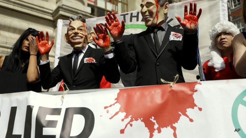 Protesters wearing a former British Prime Minister Tony Blair mask, left, and former U.S. President George W. Bush mask pose for the media outside the Queen Elizabeth II Conference Centre in London, shortly before the publication of the Chilcot report into the Iraq war, Wednesday, July 6, 2016. The long awaited British inquiry into the 2003 invasion of Iraq has been published. Led by former senior civil servant John Chilcot, the report took over seven years to prepare and runs over two million words. The report did not analyze the legality of the invasion and instead focused on the British decision-making process in the run up to the war in 2003.