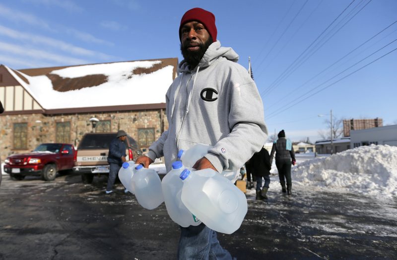 Lemott Thomas carries free water being distributed at the Lincoln Park United Methodist Church in Flint, Mich., Tuesday, Feb. 3, 2015. The city gets tap water from the Flint River, but residents have complained about the smell, taste and appearance. The city says the water is safe to drink. The federal government, however, has cited Flint for high levels of a disinfectant byproduct. (AP Photo/Paul Sancya)