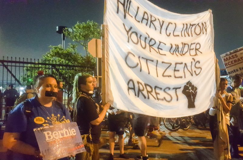 In this July 28, 2016 photograph, activists hold a banner that reads "Hillary Clinton, You're Under Citizens Arrest" outside the Wells Fargo Center in Philadelphia, site of the 2016 Democratic National Convention. (Kit O'Connell)