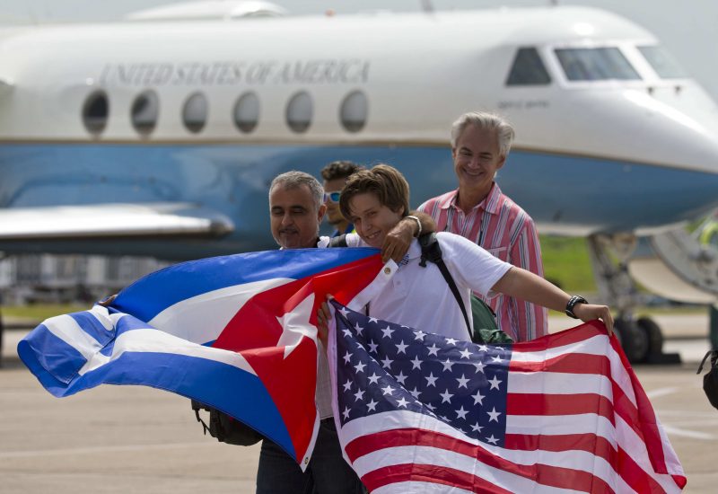 In this Aug. 31, 2016 photo, passengers of JetBlue flight 387 holding a United States, and Cuban national flags, pose for photos in front of the plane transporting U.S. Transportation Secretary Anthony Foxx, at the airport in Santa Clara, Cuba. JetBlue 387, the first commercial flight between the U.S. and Cuba in more than a half century, landed in the central city of Santa Clara on Wednesday morning, re-establishing regular air service severed at the height of the Cold War. (AP Photo/Ramon Espinosa)