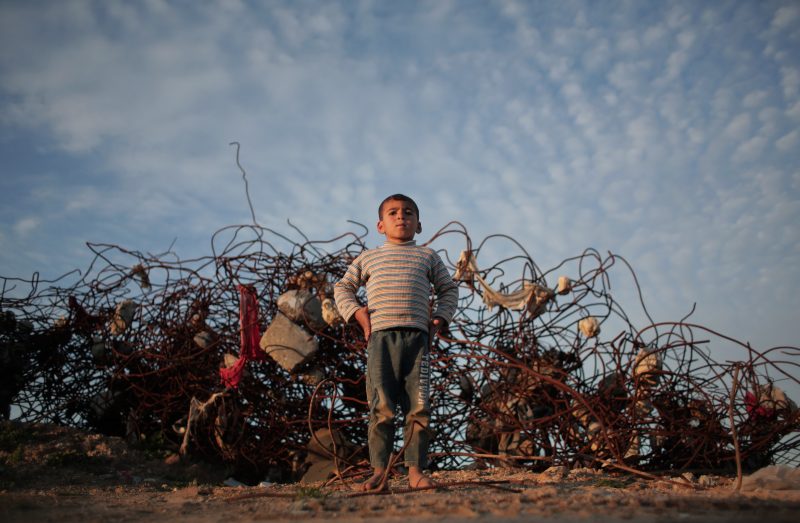 A Palestinian barefoot boy stands next to remains of a destroyed house in the town of Beit Hanoun, northern Gaza Strip, Monday, Jan. 4, 2016. (AP Photo/ Khalil Hamra)
