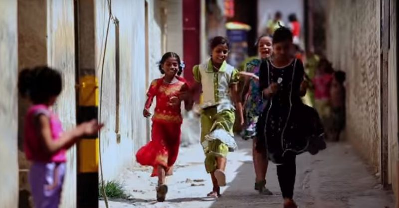 Girls run and play in a stone alleyway. (Girl Rising)