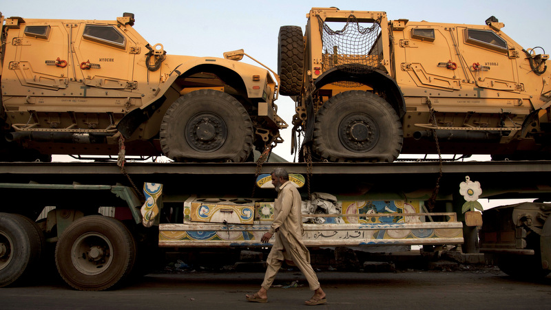 In this Nov. 26, 2013, file photo, a Pakistani man walks by a truck carrying NATO military vehicles at a terminal in Karachi, Pakistan. (AP Photo/Shakil Adil, File)
