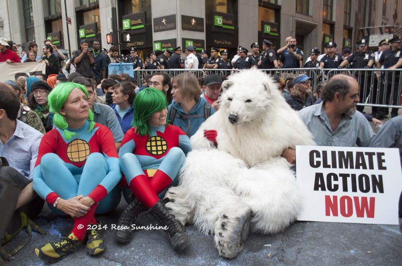 During a sit-in on a New York City street, one activist holds a sign reading "Climate Action Now." Another is dressed as a polar bear and two are dressed as Planeteers from Captain Planet. September 21, 2014. (Flickr / Resa Sunshine, CC ND)