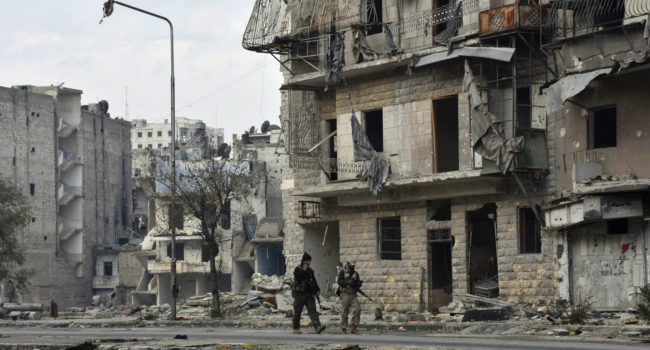 Syrian army soldiers march through the streets in the Ansari neighborhood, east Aleppo, Syria, Friday, Dec 23, 2016. (SANA via AP)