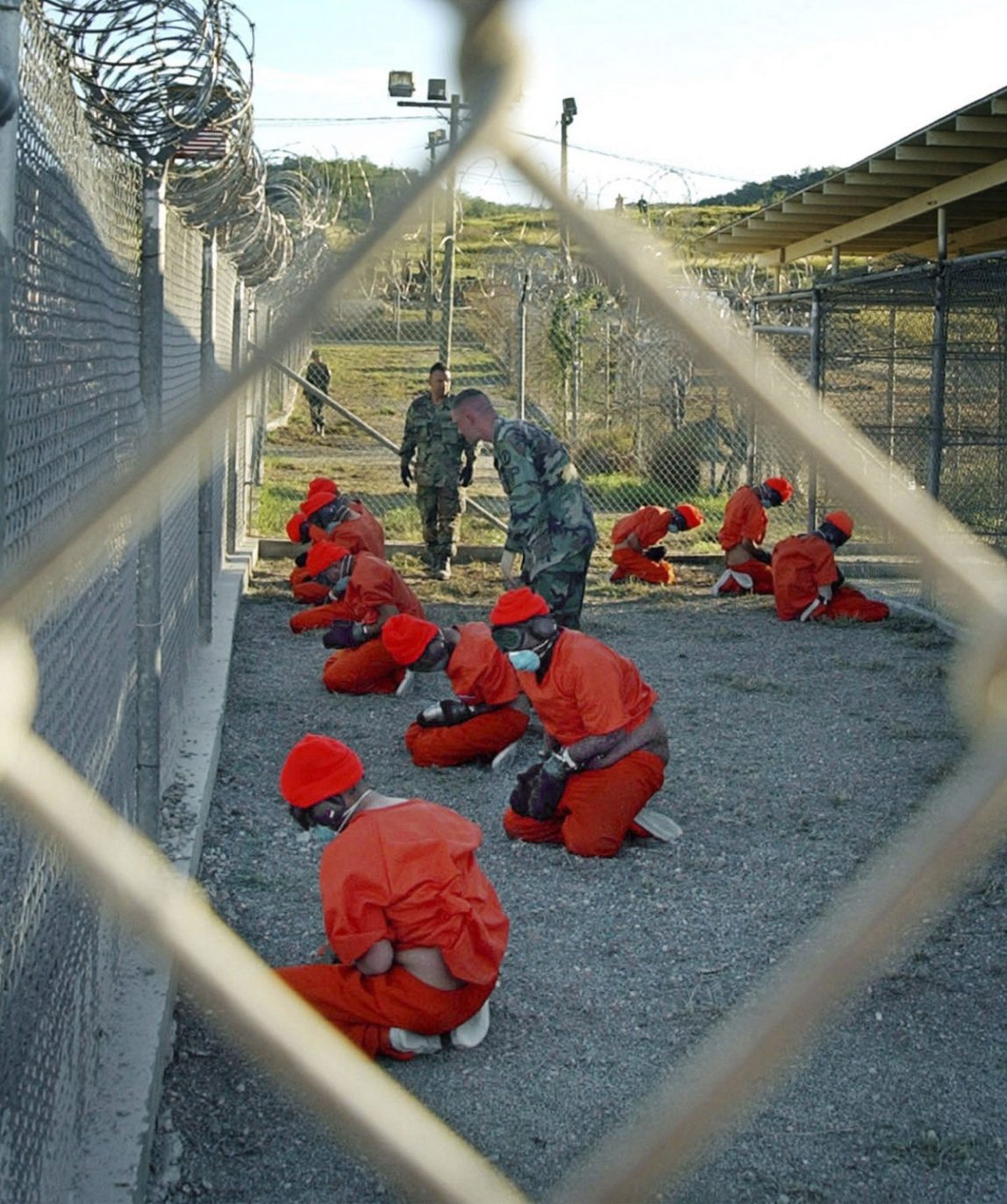 In this Jan. 11, 2002 file photo, released by the U.S. Department of Defense, detainees wearing orange jump suits sit in a holding area as military police patrol during in-processing at the temporary detention facility Camp X-Ray on Guantanamo Bay U.S. Naval Base in Cuba. (AP Photo/U.S. Navy, Shane T.McCoy, File)