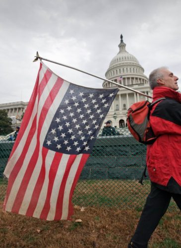 Rit Picone of Newpaltz, N.Y., carries an American flag upside down as a symbol of protest as demonstrators aligned with the Occupy Wall Street movement gathered on Capitol Hill in Washington, Tuesday, Jan. 17, 2012, to decry the influence of corporate money in politics. (AP Photo/J. Scott Applewhite)