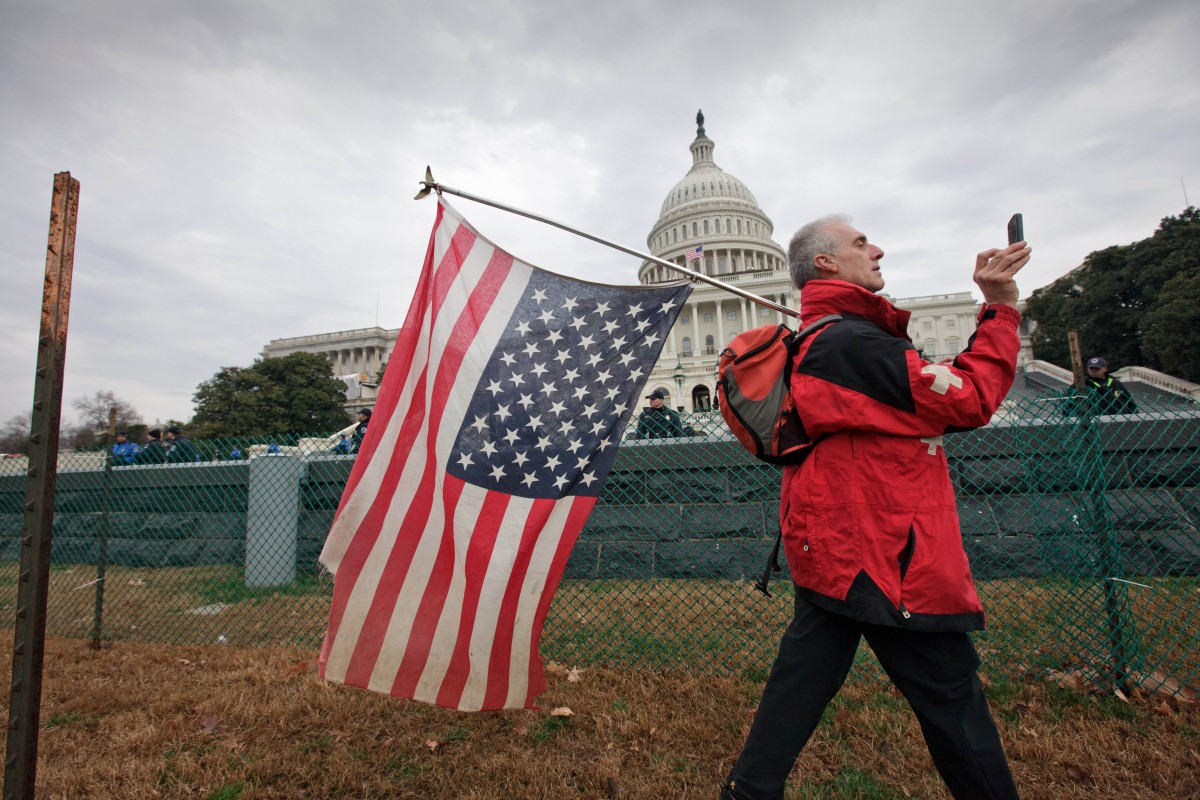 Rit Picone of Newpaltz, N.Y., carries an American flag upside down as a symbol of protest as demonstrators aligned with the Occupy Wall Street movement gathered on Capitol Hill in Washington, Tuesday, Jan. 17, 2012, to decry the influence of corporate money in politics. (AP Photo/J. Scott Applewhite)