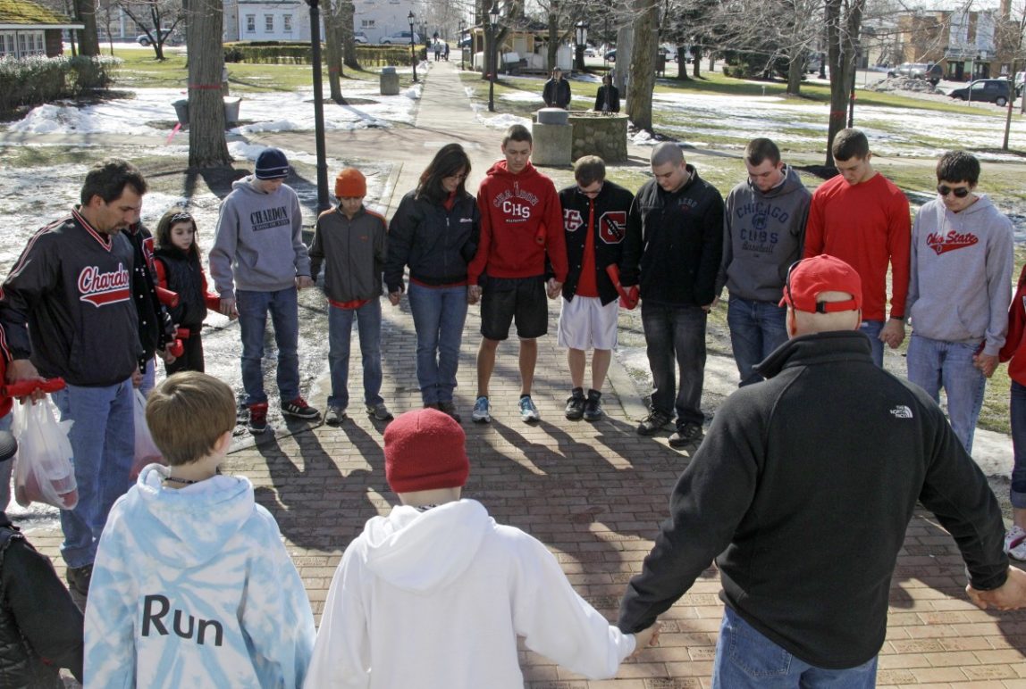 A group of students and parents pray for victims of a school shooting on the square in Chardon, Ohio Tuesday, Feb. 28, 2012. A gunman opened fire inside the Chardon High School cafeteria at the start of the school day Monday. Two of the victims have died and wounding three remain hospitalized. (AP Photo/Mark Duncan)