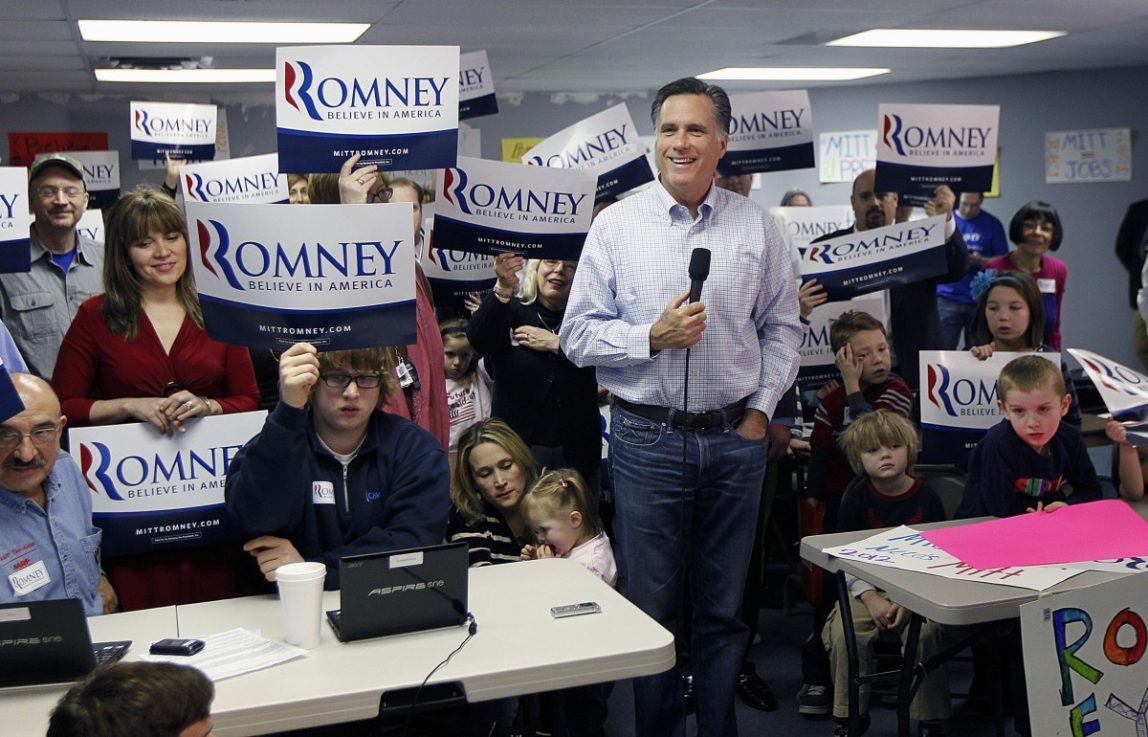 Volunteers hold up signs behind Republican presidential candidate, former Massachusetts Gov. Mitt Romney as he takes questions from reporters while visiting a campaign call center in Livonia, Mich., Tuesday, Feb. 28, 2012. (AP Photo/Gerald Herbert)