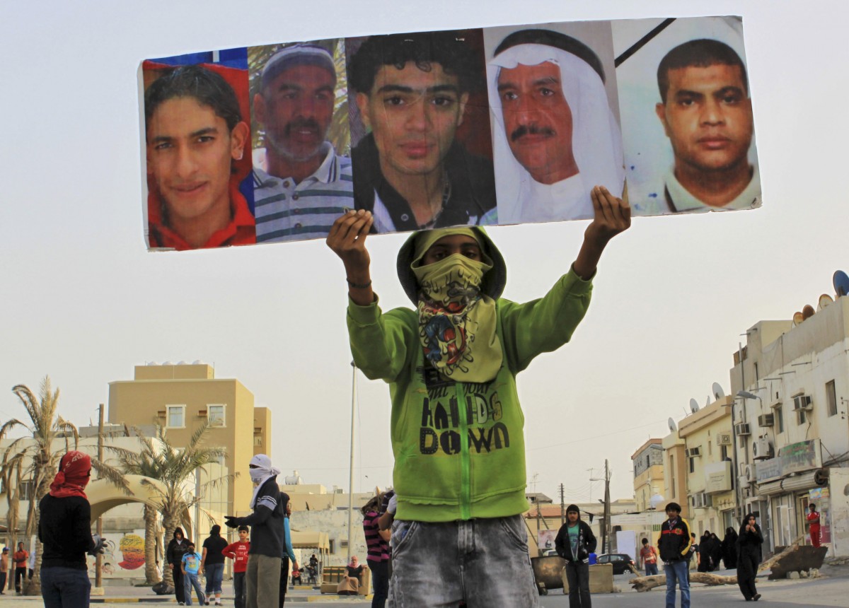 A Bahraini anti-government protester carries pictures of some of the residents of the area who have died during the past year's unrest in the Gulf island kingdom during a demonstration Thursday, March 8, 2012, in Saar, Bahrain, west of the capital of Manama. Clashes erupted with riot police firing tear gas and some protesters throwing Molotov cocktails and stones. (AP Photo/Hasan Jamali)