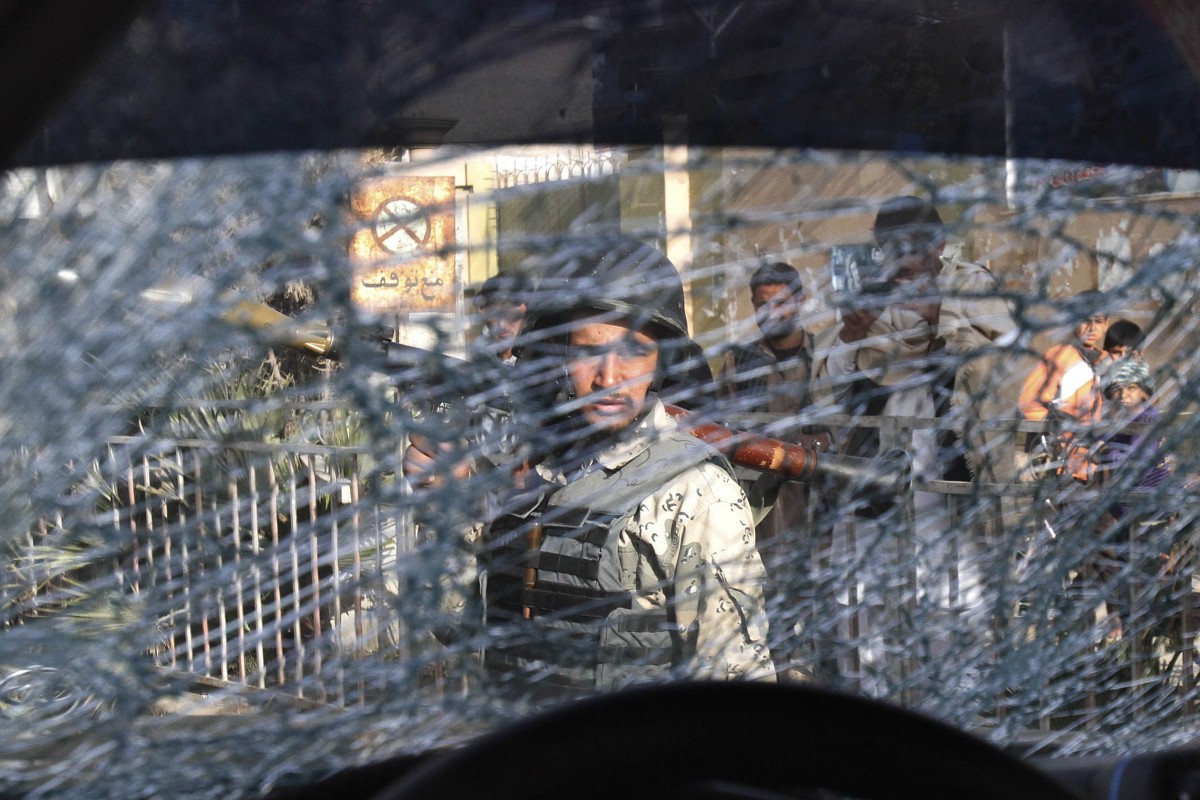 An Afghan soldier passes by a chattered window of a destroyed police car after an explosive device went off in the center of Jalalabad, east of Kabul, Afghanistan, Tuesday, March 6, 2012. The explosion wounded three policemen. (AP Photo/Rahmat Gul)