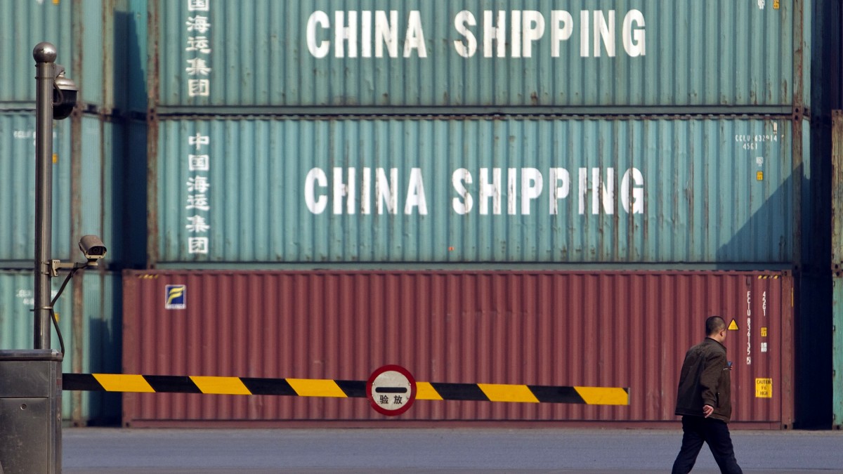 In this photo taken Tuesday, Feb. 28, 2012, a man walks near an entrance of a container port in Tianjin, China. (AP Photo/Alexander F. Yuan)