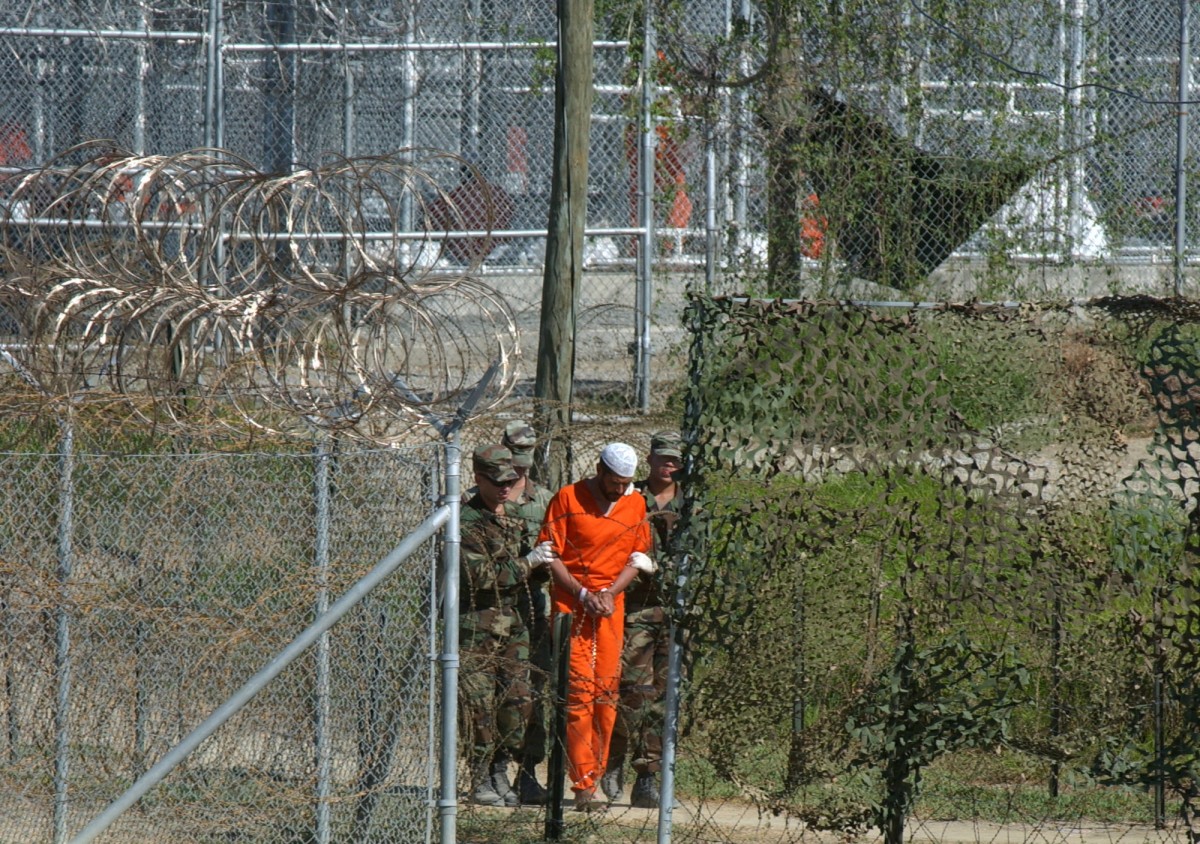 In this March 1, 2002 file photo, a detainee is escorted to interrogation by U.S. military guards in the temporary detention facility Camp X-Ray at the Guantanamo Bay U.S. Naval Base in Cuba. (AP Photo/Andres Leighton, File)