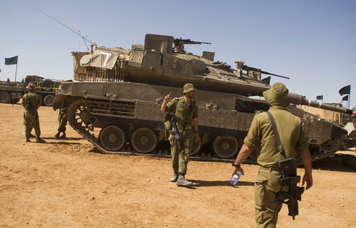 In this Oct. 12, 2010 file photo, Israeli soldiers walk next to the tank Merkava "Mark 4" as they take part in a large military exercise at the Shizafon Armored Corps Training Base in the Arava desert, north of the city of Eilat, southern Israel. (AP Photos/Dan Balilty, File)