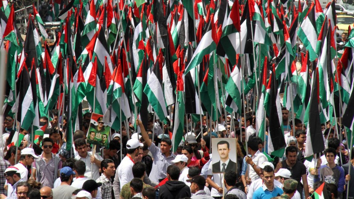 Pro-Syrian government demonstrators hold Baath party flags and a picture of President Bashar Assad at a rally at Sabe Bahrat Square to commemorate the 65th anniversary of the foundation of the Ruling Baath Arab Socialist Party in Damascus, Syria, Saturday, April 7, 2012. (AP Photo Bassem Tellawi)