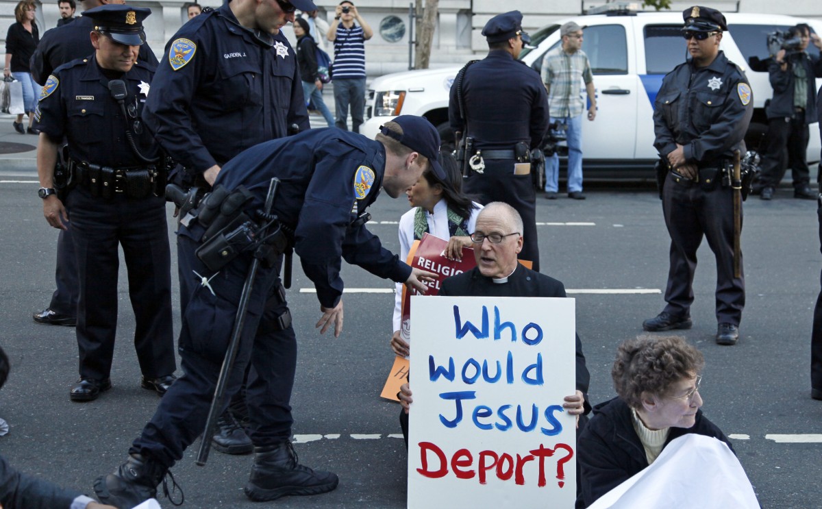 A protester sitting on Seventh Street is led away by police during an immigration reform protest outside a federal building in San Francisco, Wednesday, July 28, 2010. (AP Photo/Eric Risberg)