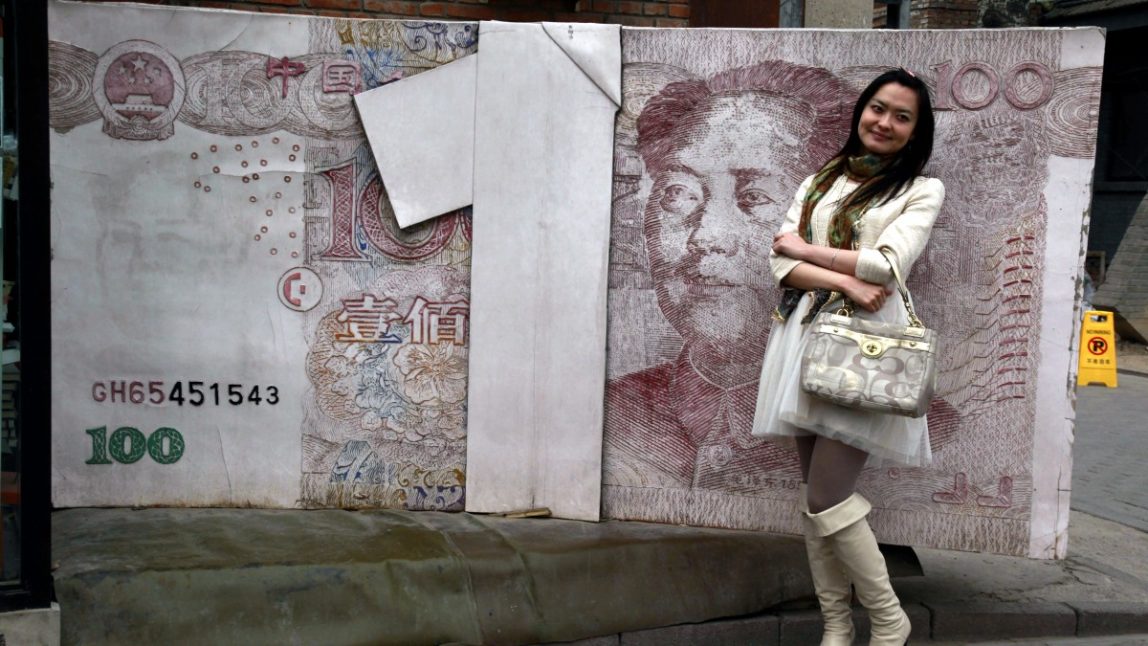 In this picture taken March 15, 2012 show a Chinese woman poses for photos near a sculpture depicting the Chinese yuan note at an art district in Beijing, China. Premier Wen Jiabao, China's top economic official, says its state-owned banks are monopolies that must be broken up, acknowledging mounting economic and political pressure to reform an industry whose vast profits are fueling public anger. (AP Photo/Ng Han Guan)