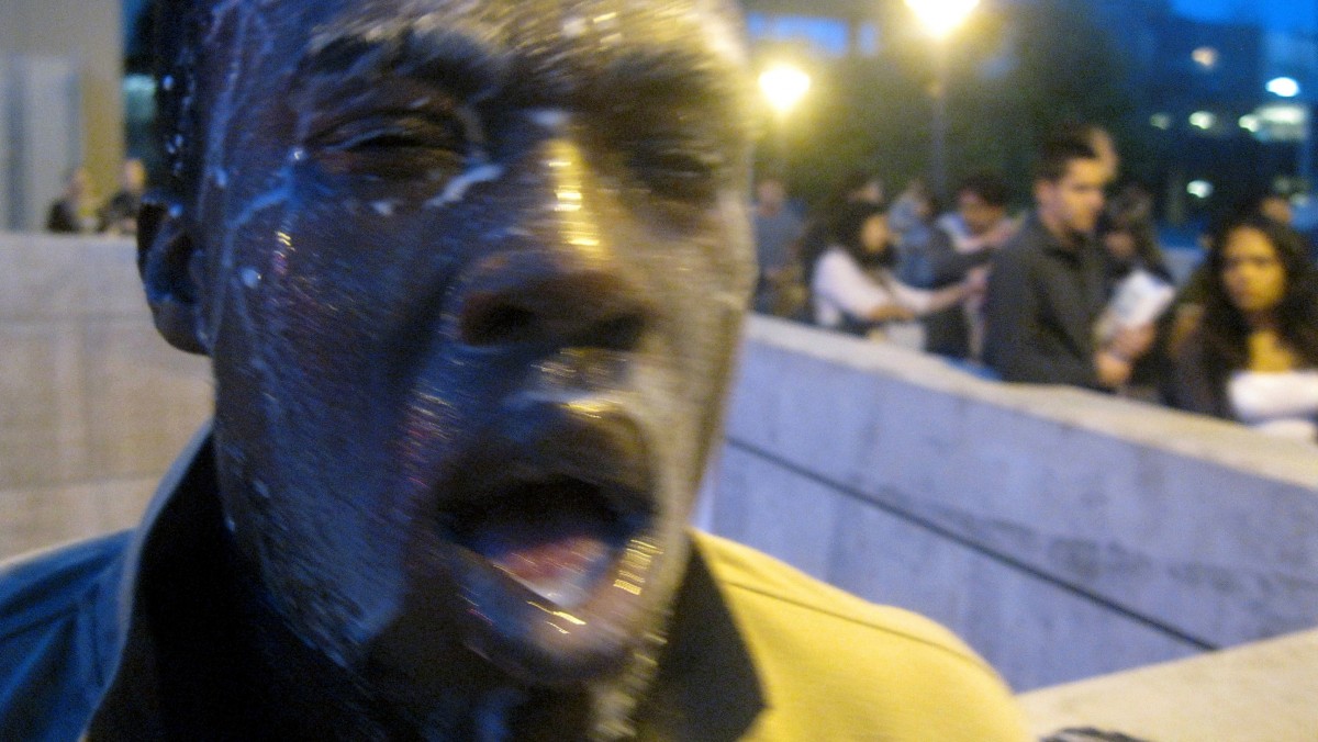 In this photo provided by David Steinman, Nnaemeka Alozie, campaign manager for Steinman, reacts with milk on his face after being sprayed with pepper spray during a protest on Tuesday, April 3, 2012, in Santa Monica, Calif. Campus police pepper-sprayed as many as 30 demonstrators after Santa Monica College students angry over a plan to offer high-priced courses tried to push their way into a trustees meeting Tuesday evening, authorities said. (AP Photo/Courtesy David Steinman)