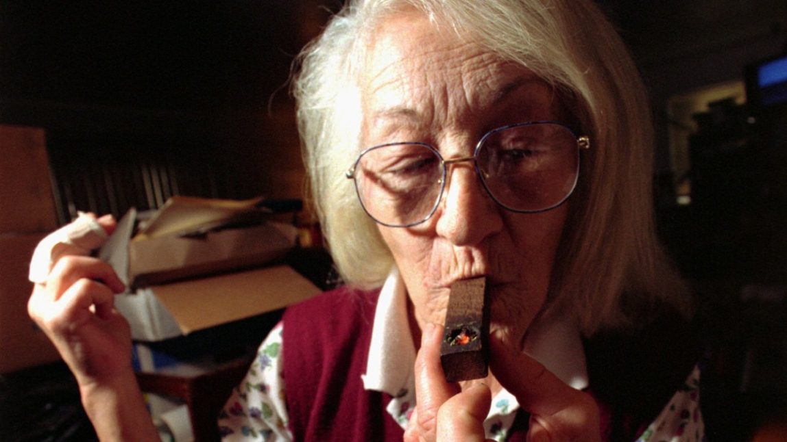 This file photo shows an elderly woman who suffers from severe arthritis and an eye condition similar to glaucoma, puffing on a pipe filled with marijuana.