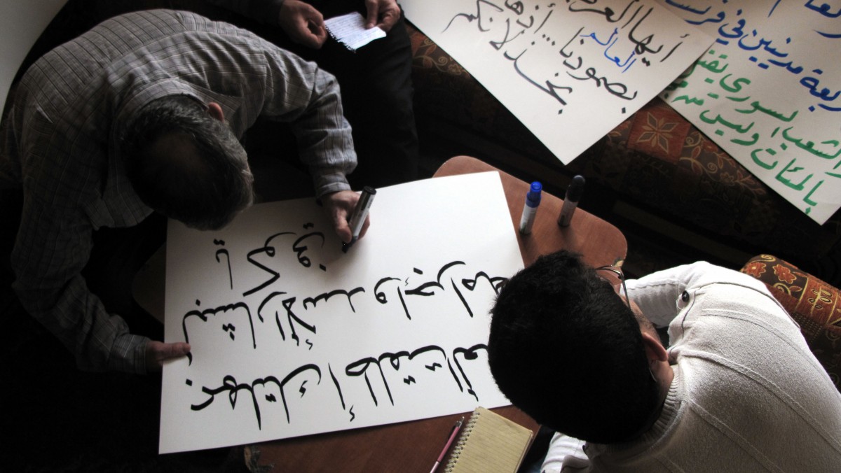 In this Tuesday, April 3, 2012 photo, Syrian activists prepare signs for upcoming protests, at a house in a neighborhood in Damascus, Syria. Syrian activists say there have been explosions and clashes in several parts of the country even as the government claims it has started to withdraw troops from some cities in compliance with an international cease-fire plan. Arabic on the poster, center, reads, "Kofi Annan, with the deadline you gave Bashar the criminal, you freed his hands for more crimes," Arabic on the poster, top left, reads, "oh Arabs, we amazed the world with our steadfastness, and you amazed the world with your silence." (AP Photo)