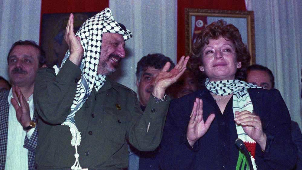 Oum Jihad, the widow of PLO second in command, Khalil al Wazir "Abu Jihad," cries as she is applauded by PLO Chairman, Yasser Arafat, on the first anniversary of her husband's assassination at a gathering in Tunis, Tunisia. (Photo Norbert Schiller)