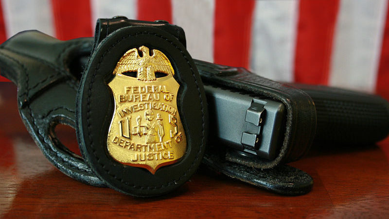 An FBI badge and service pistol are shown in this photo. (Photo by the Federal Bureau of Investigation)