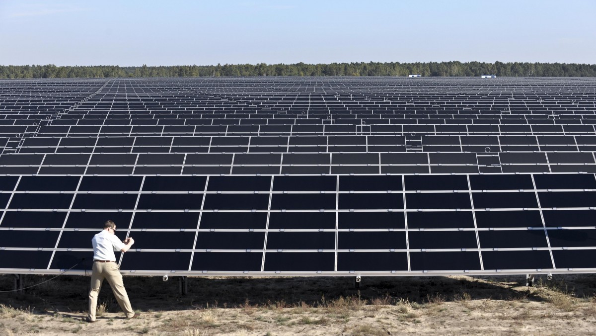 A visitor takes photographs of solar moduls in the new solar power park in Lieberose, near Cottbus, eastern Germany, Thursday, Aug. 20, 2009. The solar modules were installed on a former military training area. (AP Photo/Eckehard Schulz)?