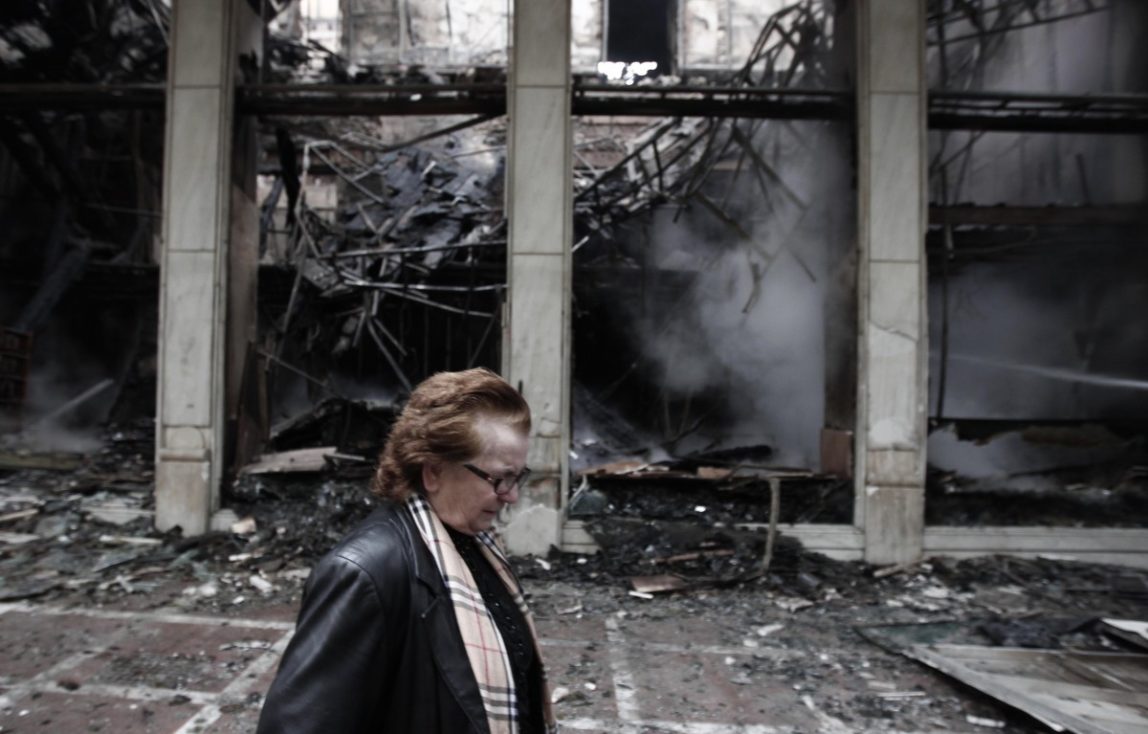 A woman walks past a destroyed building in central Athens on Monday Feb. 13, 2012. (AP Photo/Dimitri Messinis)