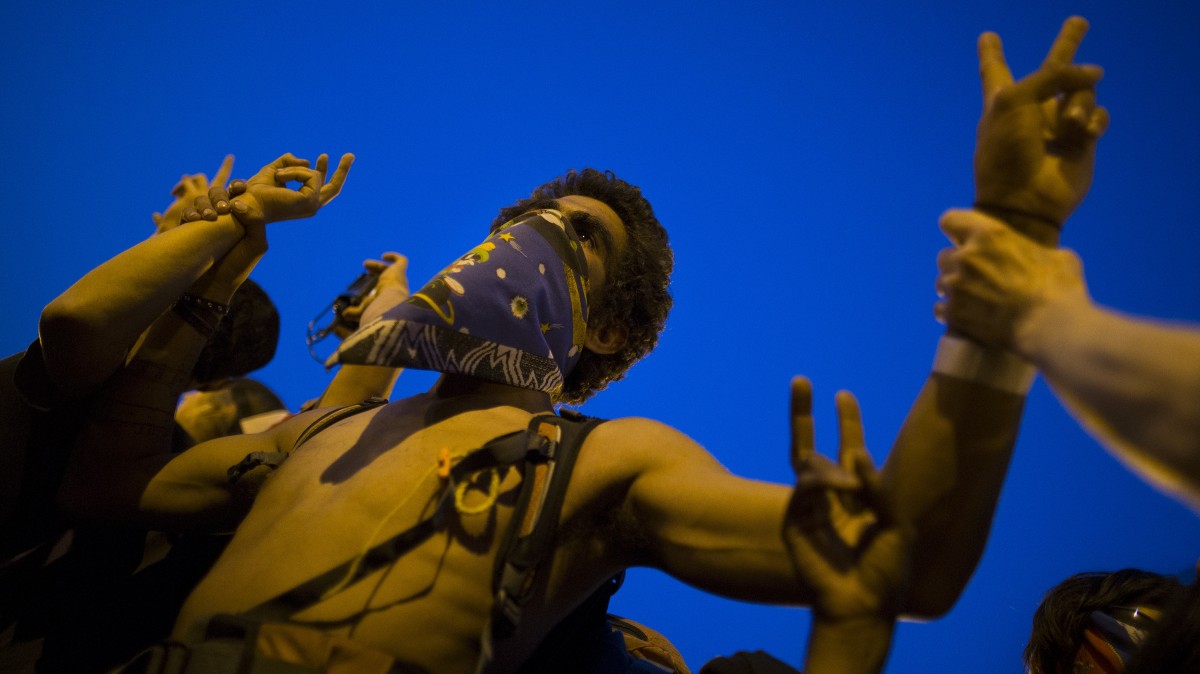 An anti-NATO protestor flashes peace signs during a march, Saturday, May 19, 2012, in Chicago. On Sunday, the start of the two-day NATO summit, thousands of protesters are expected to march to the McCormick Place convention center, where NATO delegates will be meeting. (AP Photo/John Minchillo)