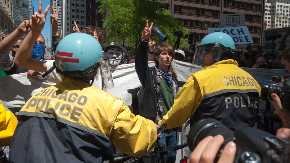 Demonstrators create peace signs with their hands, directed toward Chicago police officers while walking to Boeing's headquarters in the city. (Photo by Norbert Schiller/Mint Press)