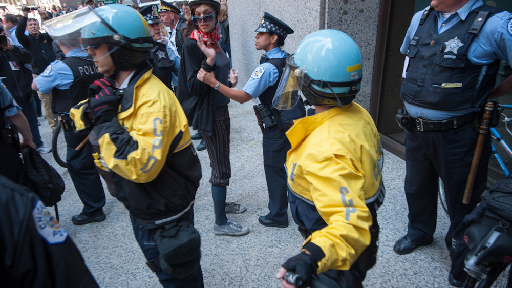 A police officer checks a demonstrator as thousands of protesters stage a peaceful march through Chicago's financial district protesting the NATO Summit taking place in the city on Monday May 21, 2012. The demonstration was organized by numerous anti-war and capitalist groups including Occupy Wall Street. (Photo Norbert Schiller/Mint Press)