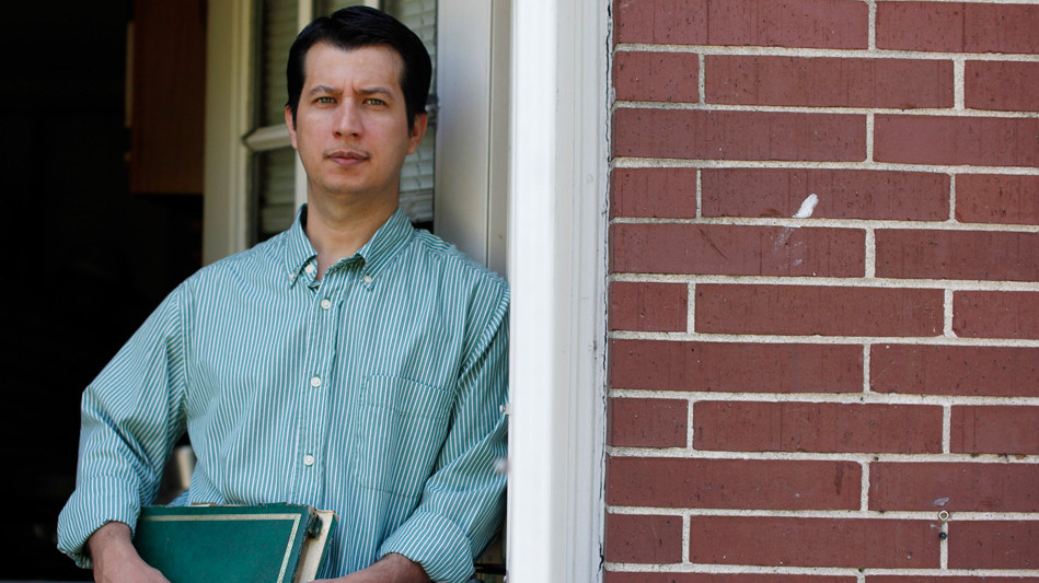 Oscar Alfredo Ramírez Castañeda holds an album containing photos of Lt. Oscar Ovidio Ramírez Ramos at the back door of his home in Framingham, Mass., on May 13, 2012. (Matthew Healey for ProPublica)