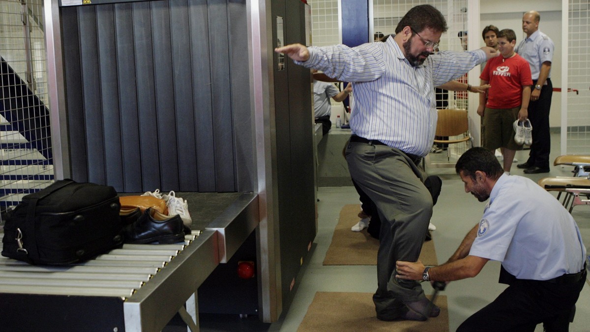 A security officerchecks a passenger at a security checkpoint. The TSA is being criticized for shelving $184 million worth of security equipment in a warehouse in Texas. (KEYSTONE/Salvatore Di Nolfi)