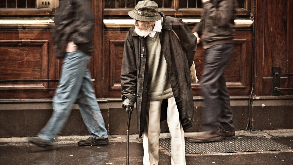 An elderly man with a cane waits for a break in the traffic. (Photo by Garry Knight)
