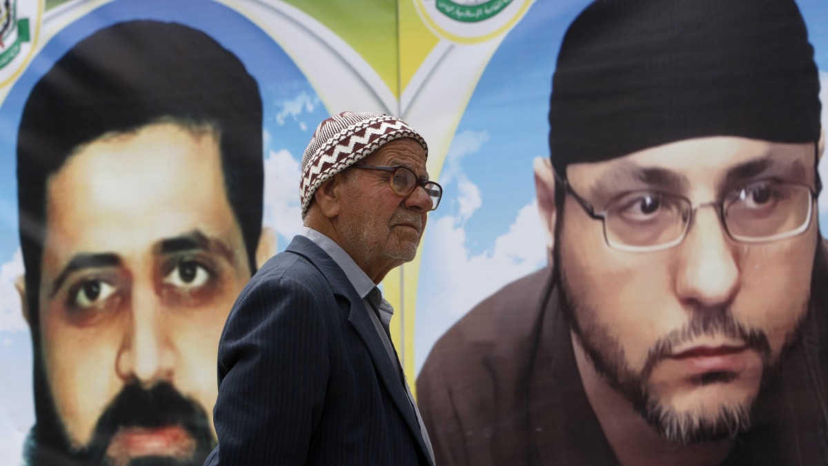 A Palestinian man looks at posters of Palestinian prisoners Mahmoud Issa, left, and Abdallah Barghouti, during a rally held by hunger striking activists in solidarity with Palestinians prisoners held in Israeli jails. (AP Photo/Adel Hana