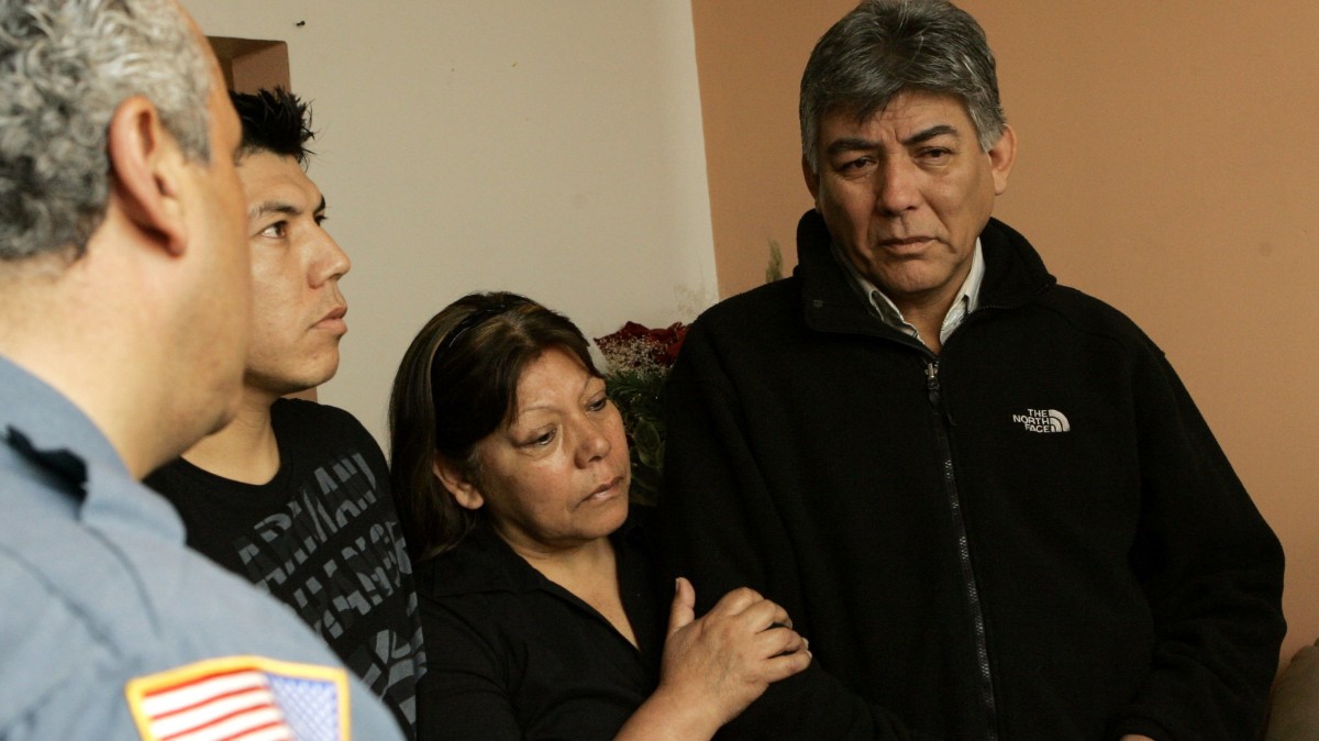 Carlos Bueno, right, and his wife, Eugenia Galdos, center, and their son, Carlos Jr., receive condolences at their home in Paterson, N.J., Wednesday, May 13, 2009, from a Paterson police officer on the death of their son, Sgt. Christian Bueno-Galdos. Bueno-Galdos, 25, is one of the soldiers who the Army says were gunned down by a comrade in a clinic in Iraq. (AP Photo/Mike Derer)