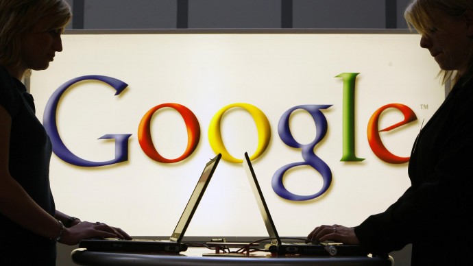 Exhibitors of the Google company work on laptop computers in front of an illuminated sign of the Google logo at the industrial fair Hannover Messe in Hanover, Germany,in this April 17, 2007 file photo. (AP Photo/Jens Meyer, file)