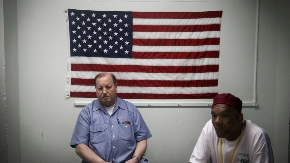Inmates John E. Barba, left, and Frederic Jones, both U.S. Navy veterans sit in front of an American flag. A new jail in Georgia exclusively houses veterans who are incarcerated. (AP Photo/Jason Turner)