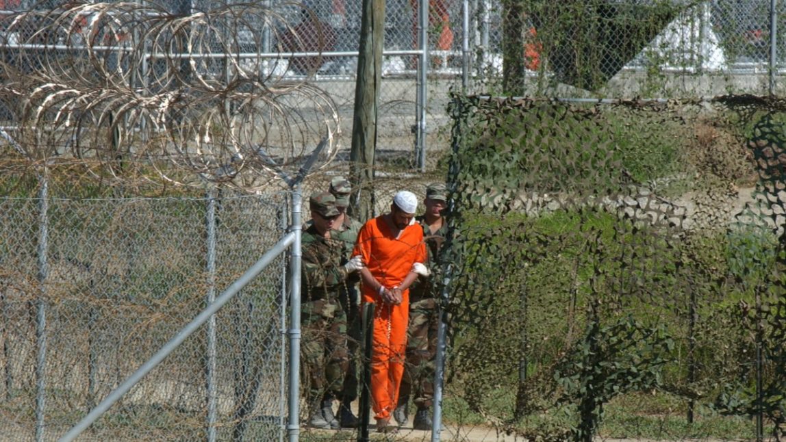 A detainee is escorted to interrogation by U.S. military guards in the temporary detention facility Camp X-Ray at the Guantanamo Bay U.S. Naval Base in Cuba. (AP Photo/Andres Leighton, File)