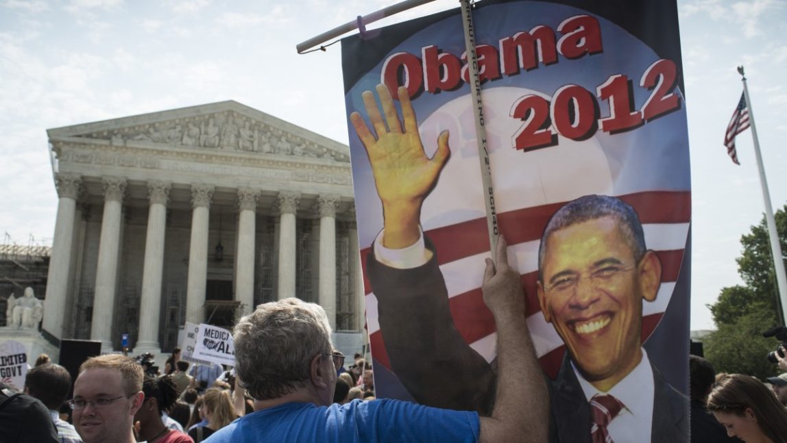 An unidentified man carries a banner of President Obama at the steps of the U.S. Supreme Court in Washington, DC, June 28, 2012. (Mannie Garcia / MintPress News 2012)