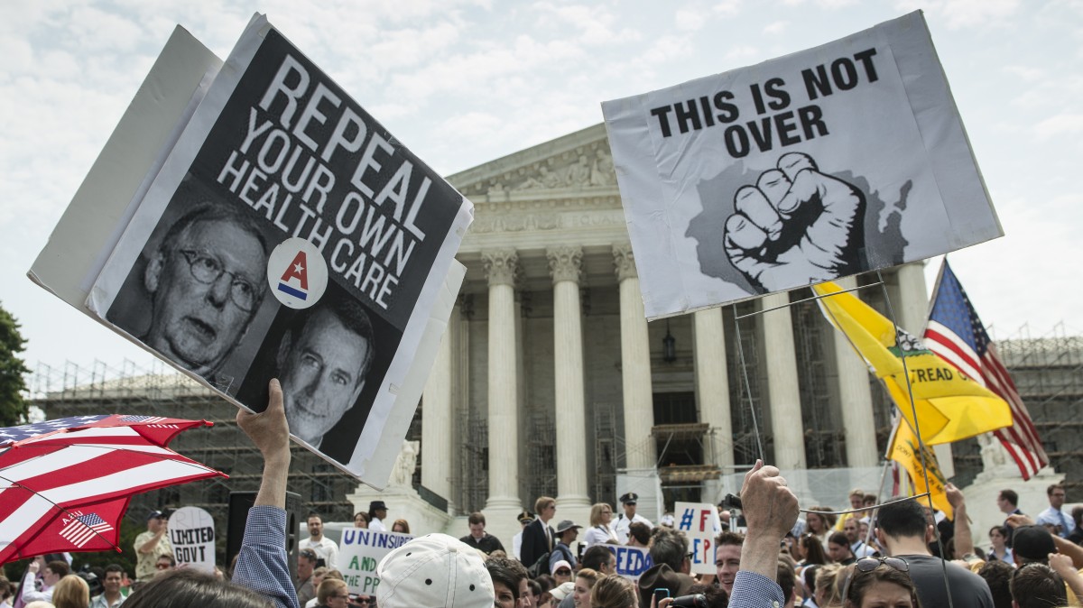 An unidentified man holds up two signs on the steps of the U.S. Supreme Court in Washington, DC, June 28, 2012. (Mannie Garcia / MintPress News 2012)